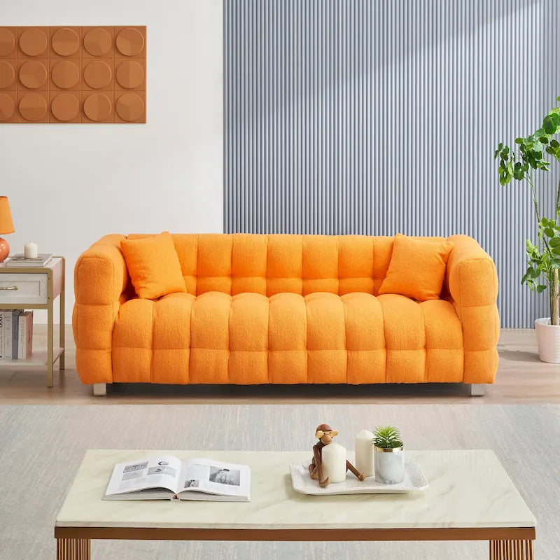 Canapé trois places orange avec deux coussins et des pieds en métal robustes