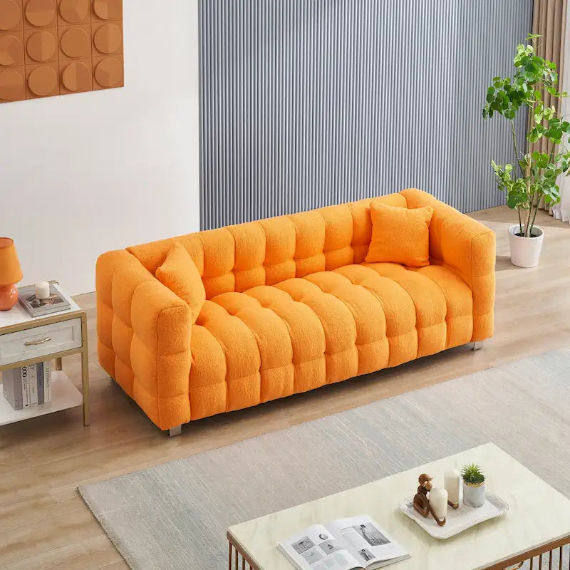 Canapé trois places orange avec deux coussins et des pieds en métal robustes